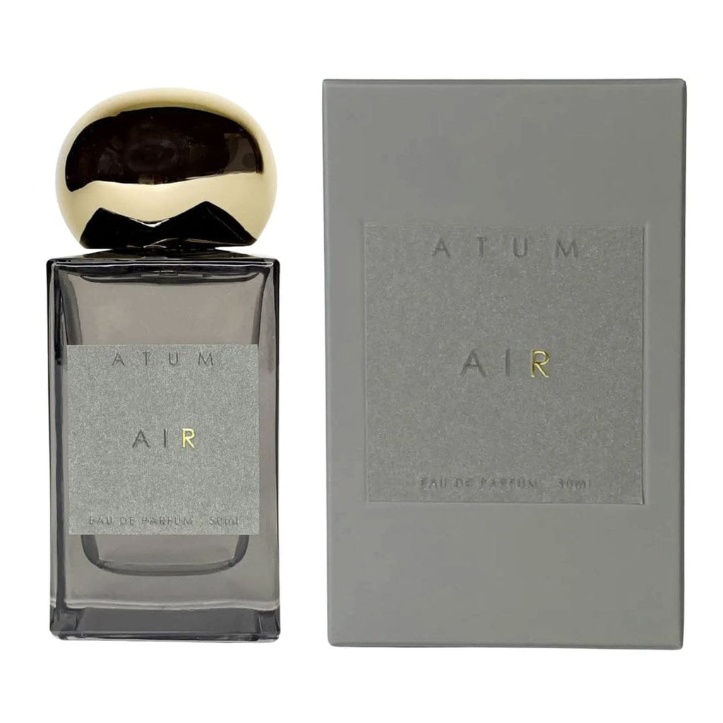 A bottle of AIR Eau de Parfume Fragrance next to its textured gray packaging box, featuring a metallic gold cap and a gray label.