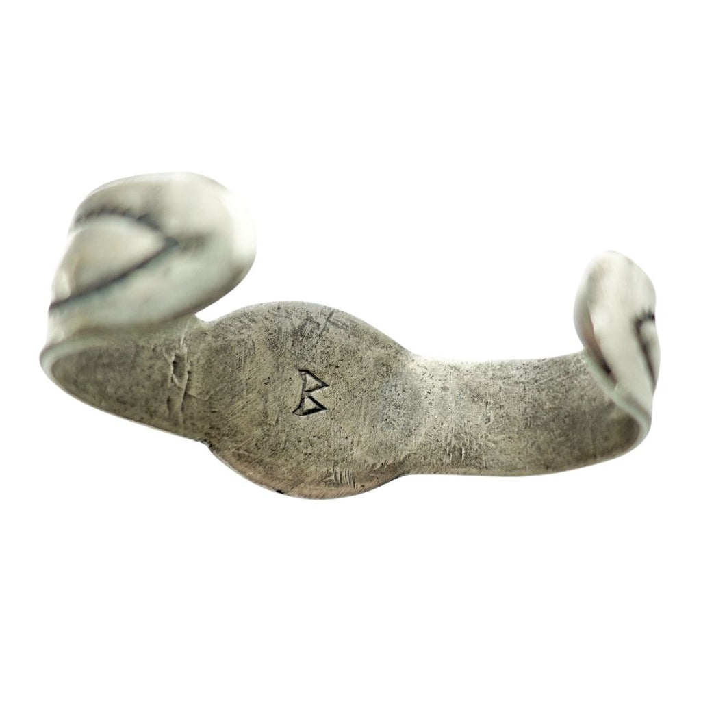 A handmade sterling silver cuff bracelet with organic, sculptural ends and a Hallmark  letter 'B' in the center, for Navajo artist BUFFALO shown on a plain white background.