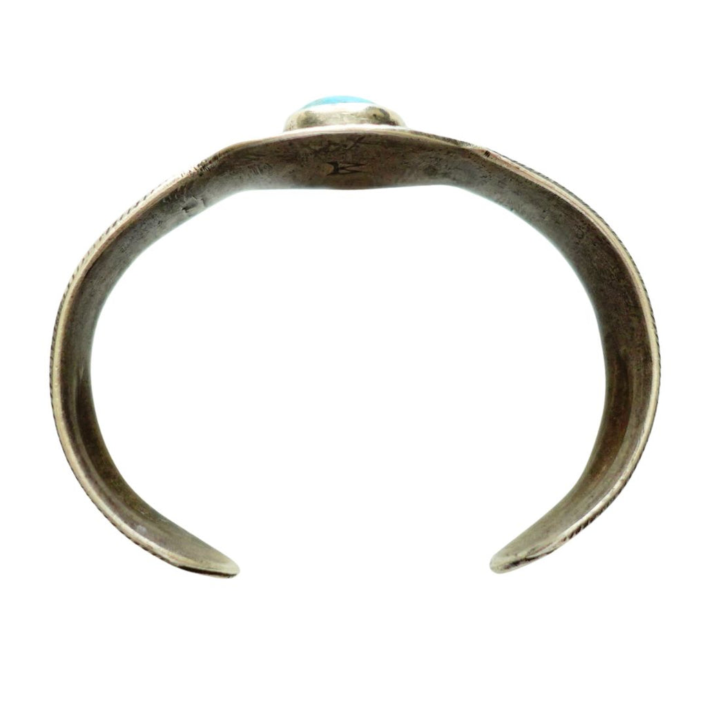 A ingot silver cuff ring featuring a central turquoise cabochon stone with natural matrix inclusions, set against a plain white background.