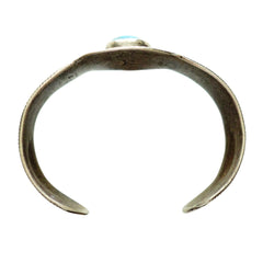 A ingot silver cuff ring featuring a central turquoise cabochon stone with natural matrix inclusions, set against a plain white background.