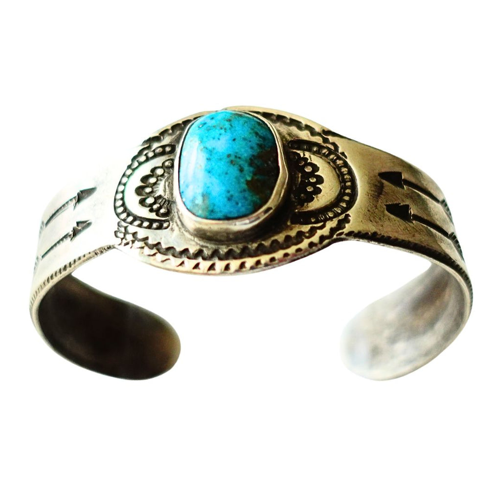 A ingot silver cuff ring featuring a central turquoise cabochon stone with natural matrix inclusions, set against a plain white background.