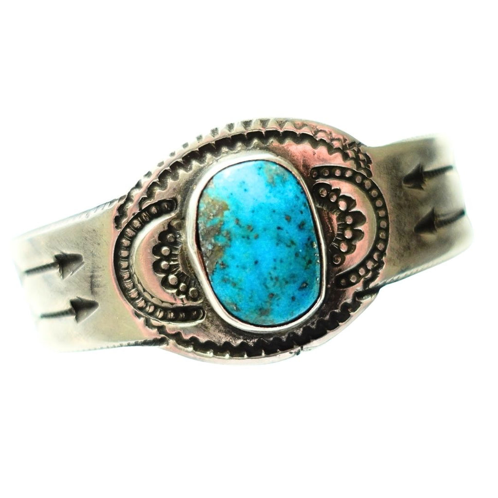 A ingot silver cuff ring featuring a central turquoise cabochon stone with natural matrix inclusions, set against a plain white background.