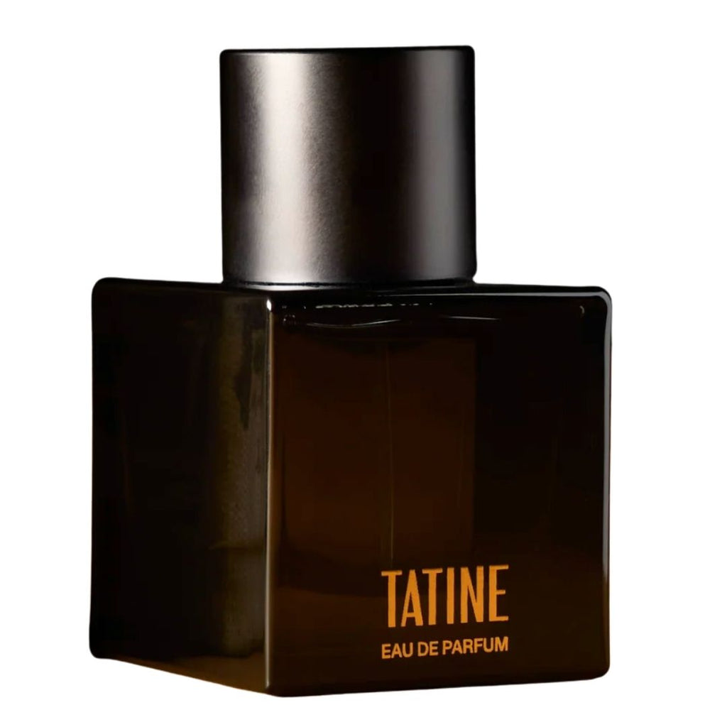 A dark brown glass perfume bottle with a matte black cap, featuring the brand name 'TATINE' in gold lettering on the front, set against a plain white background.