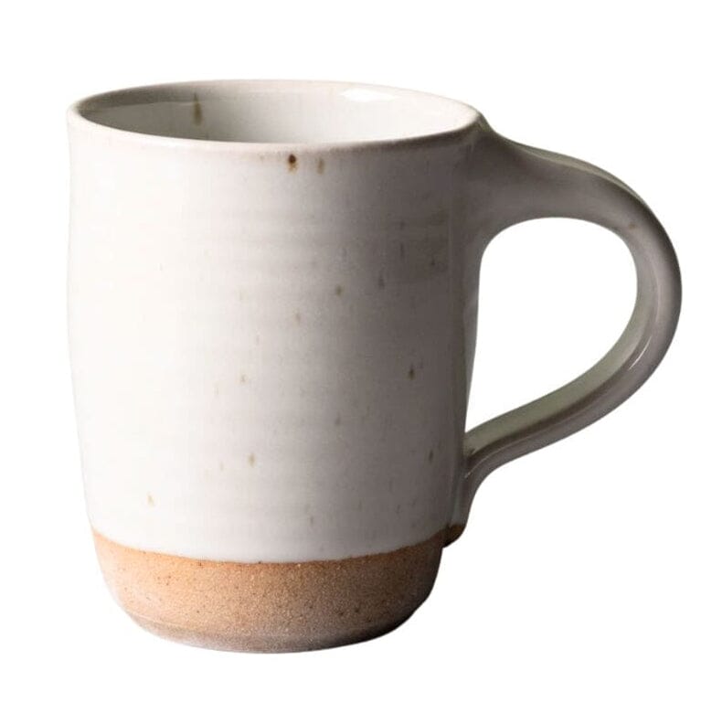 A handmade ceramic mug with a matte off-white glazed body, subtle speckles, and a natural, unglazed sandy beige base.