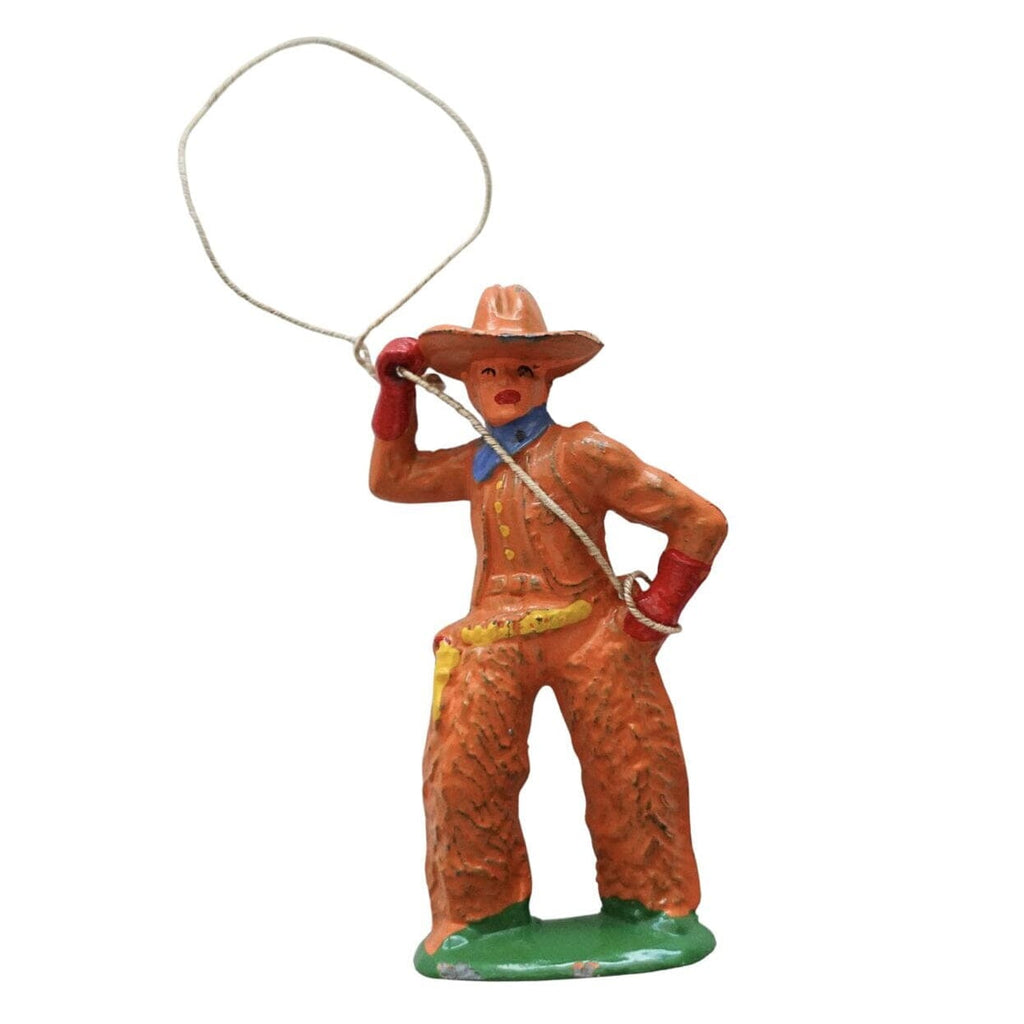 A small cowboy figurine holding a lasso, painted in orange-brown with red gloves, a blue neckerchief, yellow belt details, and a green base, isolated on a white background.