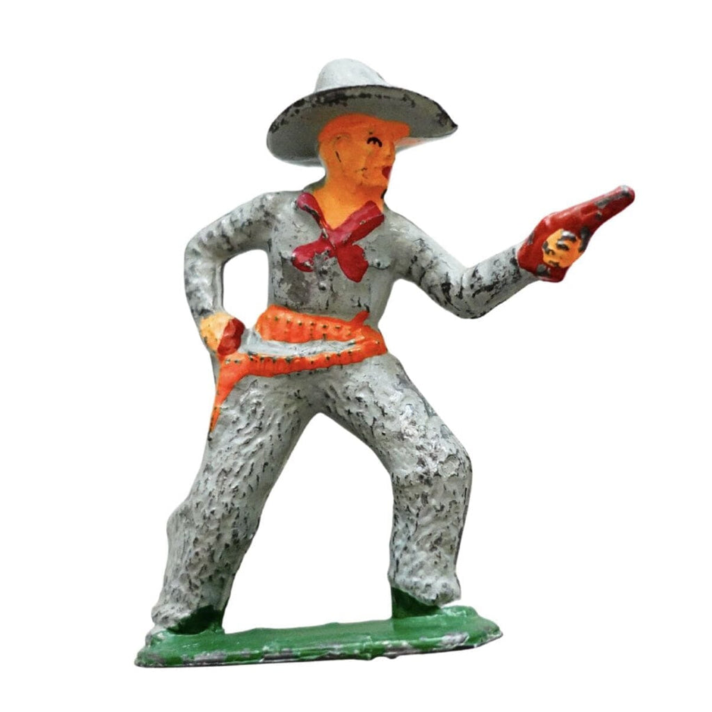 A vintage toy soldier figurine of a cowboy pointing a pistol, painted in gray, orange, white, and green on a white background.