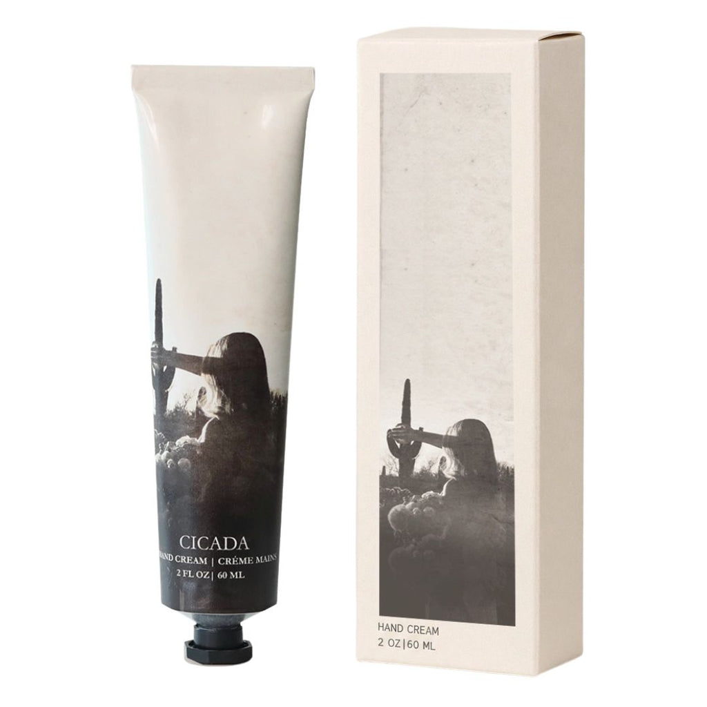A tube of Cicada Hand Cream with a black and white artistic label, shown next to its matching cream-colored packaging box on a white background.