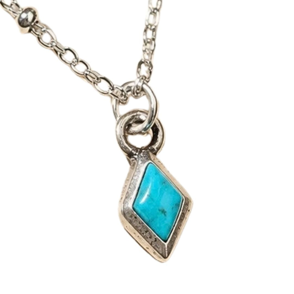 A silver chain necklace with a diamond-shaped pendant featuring a vibrant turquoise stone in a silver bezel setting, shown against a plain white background.