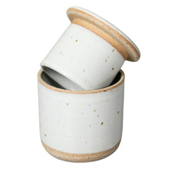 A small white ceramic lidded Butter Keeper with a matching lid resting on top, featuring subtle speckles and natural tan clay rims, set against a plain white background.