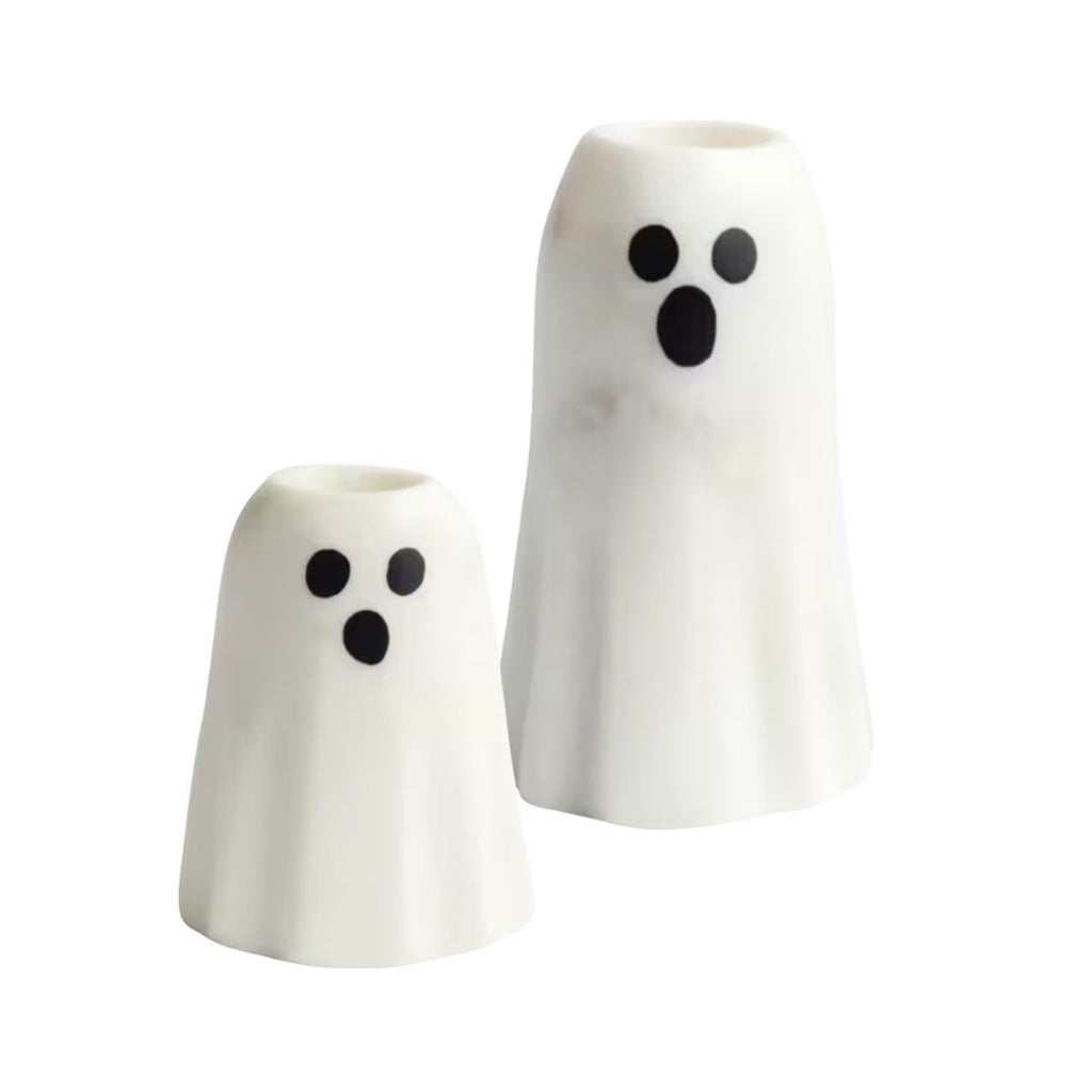 Two white ghost-shaped ceramic taper candle holders with black eyes and mouths, shown on a plain white background.