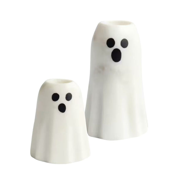 Two white ghost-shaped ceramic taper candle holders with black eyes and mouths, shown on a plain white background.
