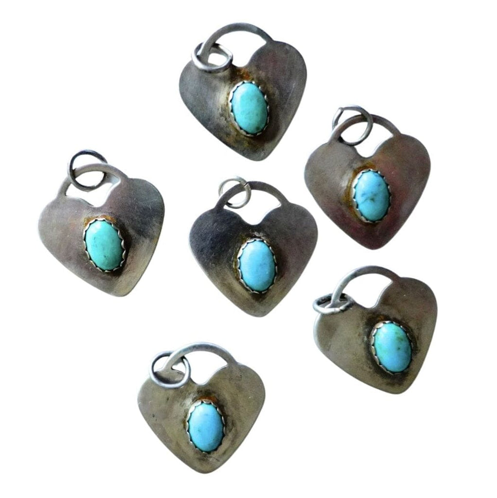 Six heart-shaped sterling silver pendants with oval turquoise stones, arranged on a plain white background.