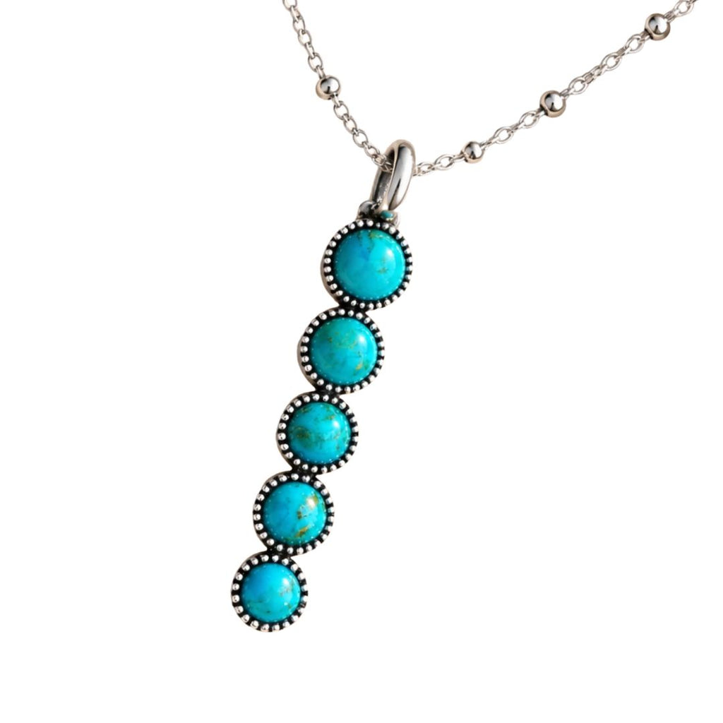 A silver-toned necklace featuring a vertical dangle pendant with five round turquoise-colored stones in dark oxidized bezel settings, suspended from a delicate silver chain against a plain white background.