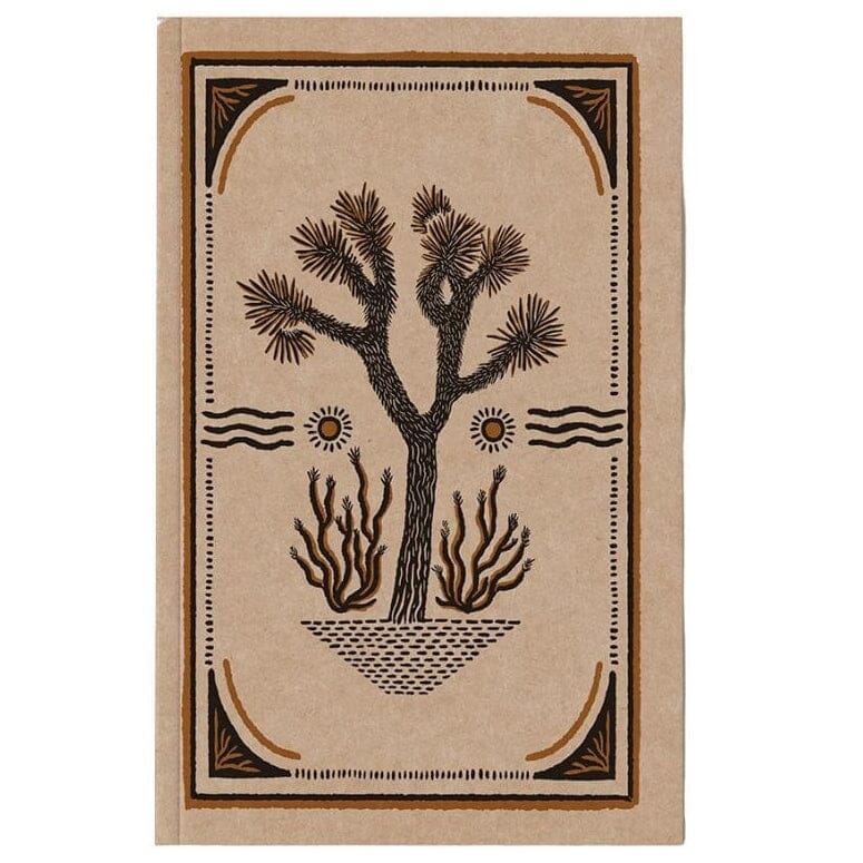 A rectangular notebook or journal with a tan cover featuring a dark brown illustration of a Joshua tree, suns, and a decorative border, shown against a plain white background.