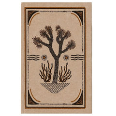 A rectangular notebook or journal with a tan cover featuring a dark brown illustration of a Joshua tree, suns, and a decorative border, shown against a plain white background.