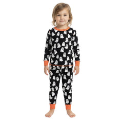 A young child wearing a two-piece Halloween pajama set with a black background, white ghost pattern, and orange trim, standing against a plain white background.