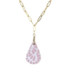 A gold paperclip chain necklace with a teardrop-shaped pendant featuring a pink and white spotted pattern, shown against a plain white background.