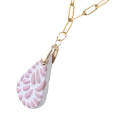 A gold paperclip chain necklace with a teardrop-shaped Talavera pendant featuring a white background and a pink leaf or petal pattern, shown against a plain white background.