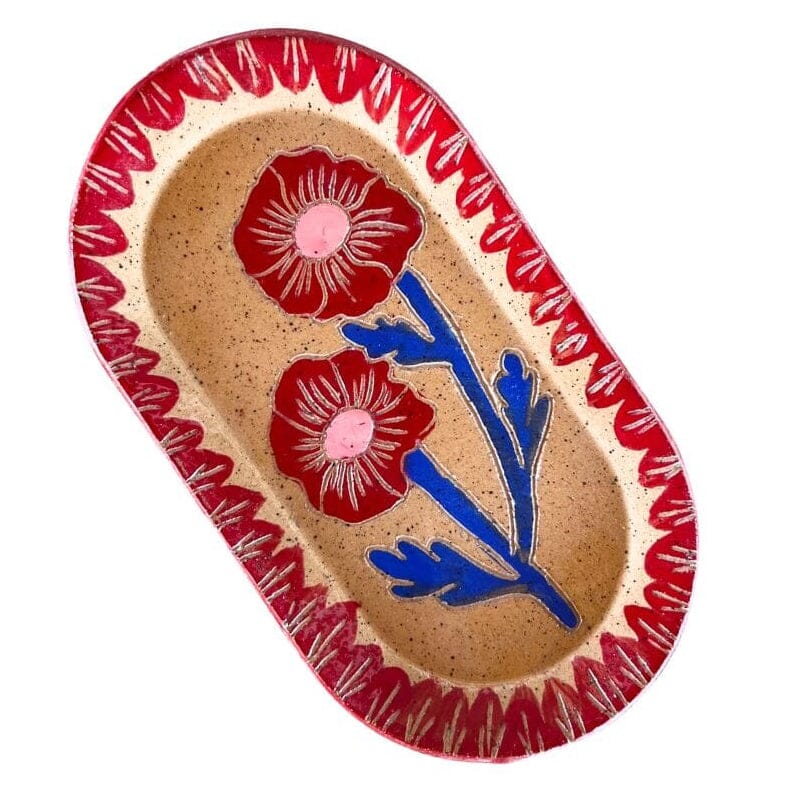 An oval ceramic trinket dish with a speckled beige interior, decorated with two red flowers with pink centers, blue stems, and a red patterned border.