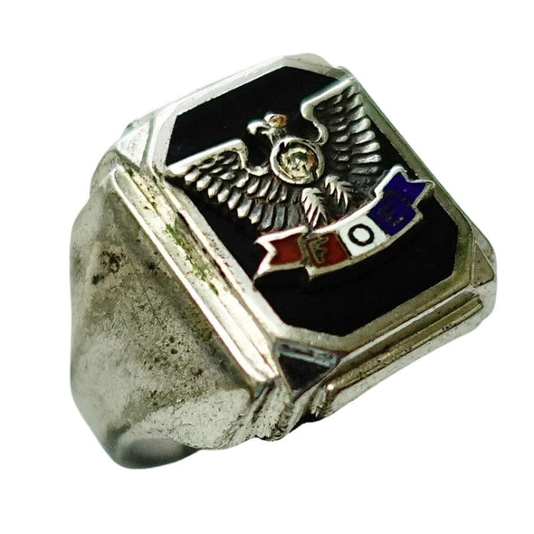 A silver-toned signet ring featuring a black enamel face with an eagle emblem and a small red, white, and blue banner, shown on a plain white background.