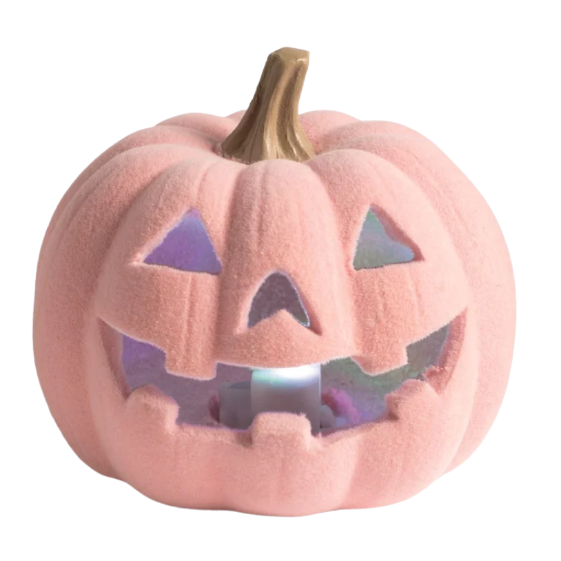 A pink plush jack-o'-lantern Halloween decoration with a carved face and a lit interior glow, shown on a plain white background.
