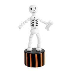 A white articulated skeleton toy figurine holding a small white bone, standing on a black cylindrical base with orange vertical stripes, isolated on a white background.