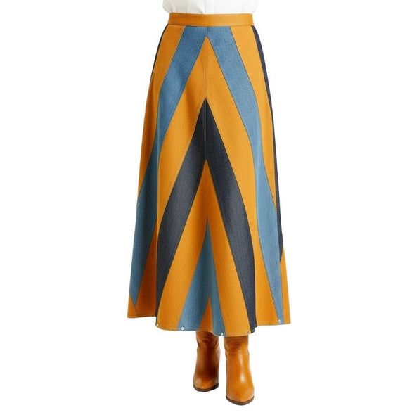 A high-waisted A-line midi skirt with a bold chevron pattern in camel brown, blue denim, styled with tan ankle boots against a white background.