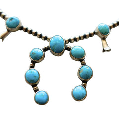 A turquoise and sterling silver Native American style necklace and matching dangle earrings on a plain white background by Navajo silversmith Jason Livingston