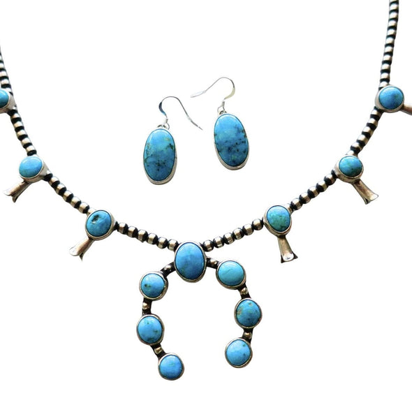 A turquoise and sterling silver Native American style necklace and matching dangle earrings on a plain white background by Navajo silversmith Jason Livingston
