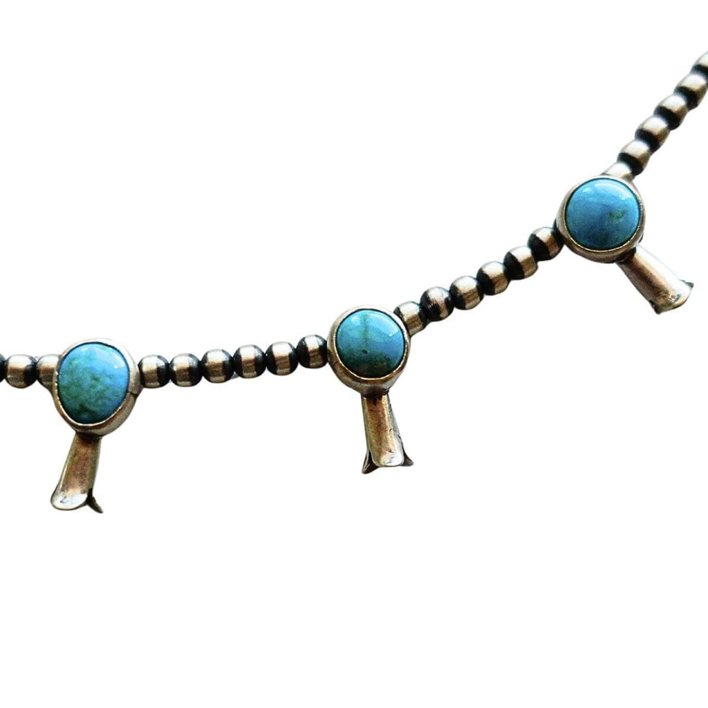 A turquoise and sterling silver Native American style necklace and matching dangle earrings on a plain white background by Navajo silversmith Jason Livingston
