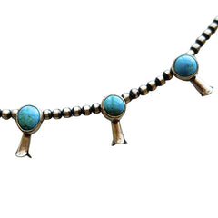 A turquoise and sterling silver Native American style necklace and matching dangle earrings on a plain white background by Navajo silversmith Jason Livingston