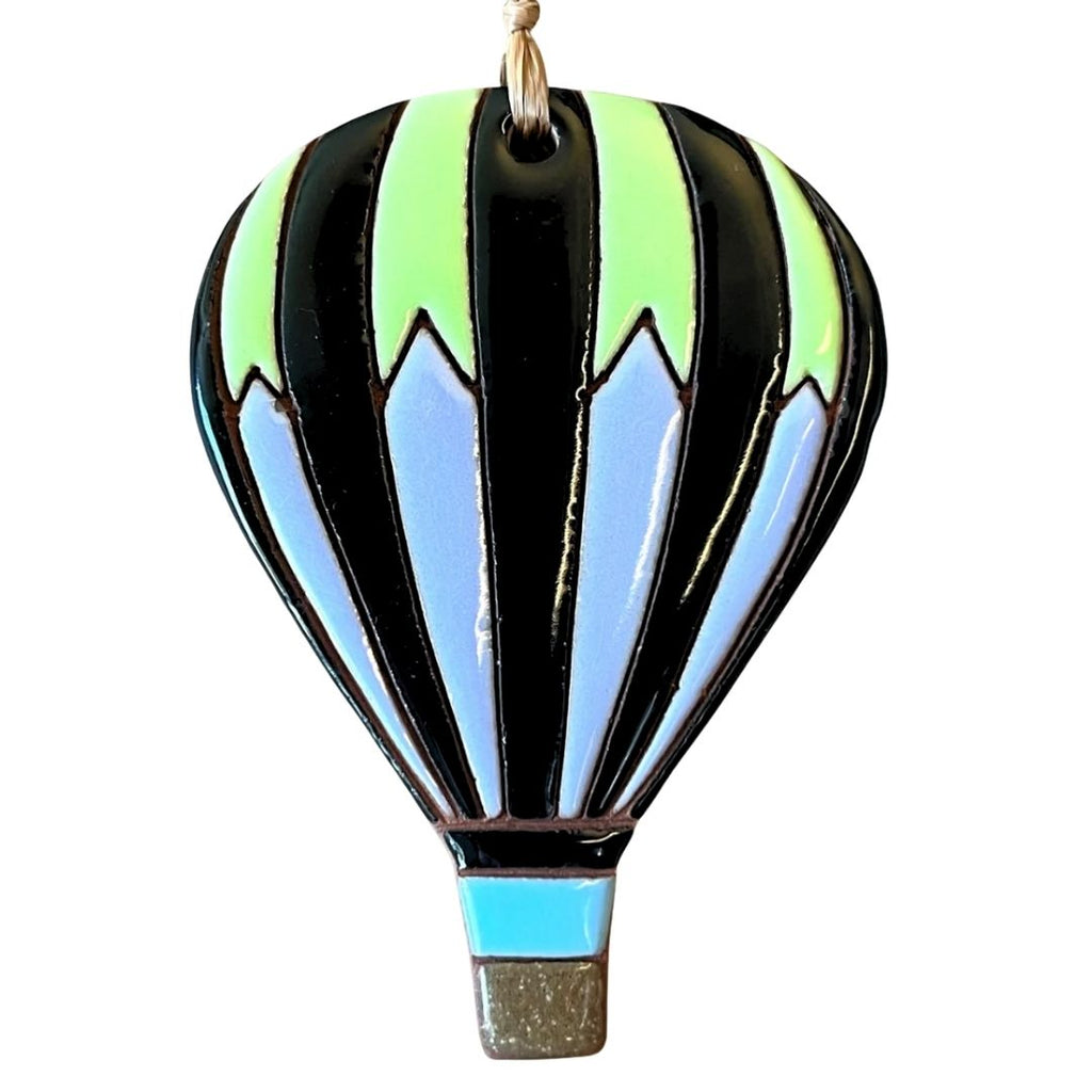 A hot air balloon ornament with black, light blue, and neon green stripes, hanging by a gold-colored string against a plain white background.