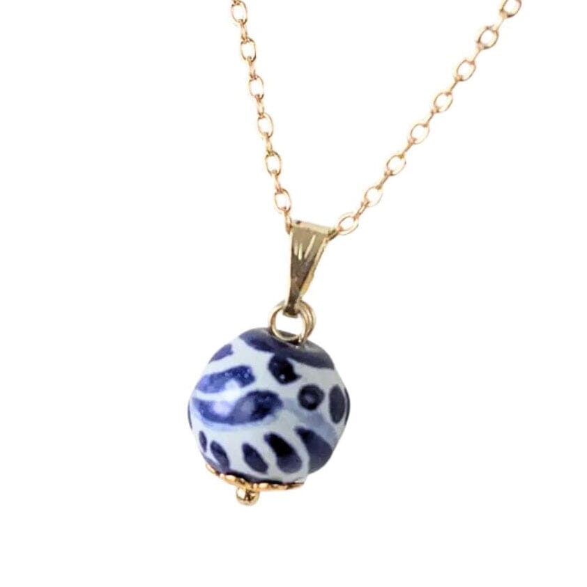 A gold chain necklace featuring a round, Talavera blue and white patterned bead pendant with a small gold cap at the bottom, shown against a plain white background.