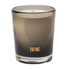 A Tatine brand scented candle in a smoky translucent glass jar with a single wick, shown against a plain white background.