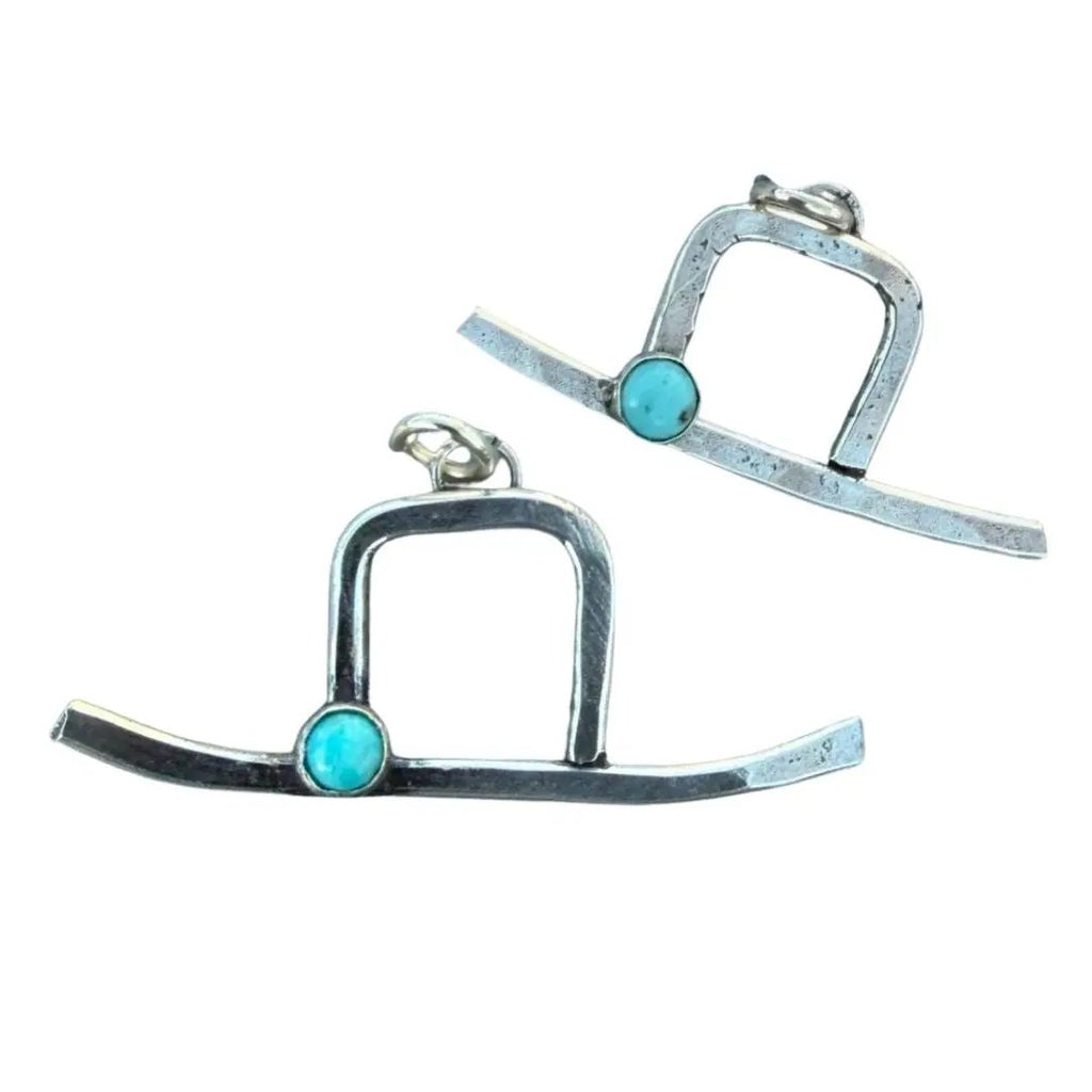 A pair of silver-toned geometric dangle earrings with a small round turquoise stone set near the base of each open arch design, shown on a plain white background.