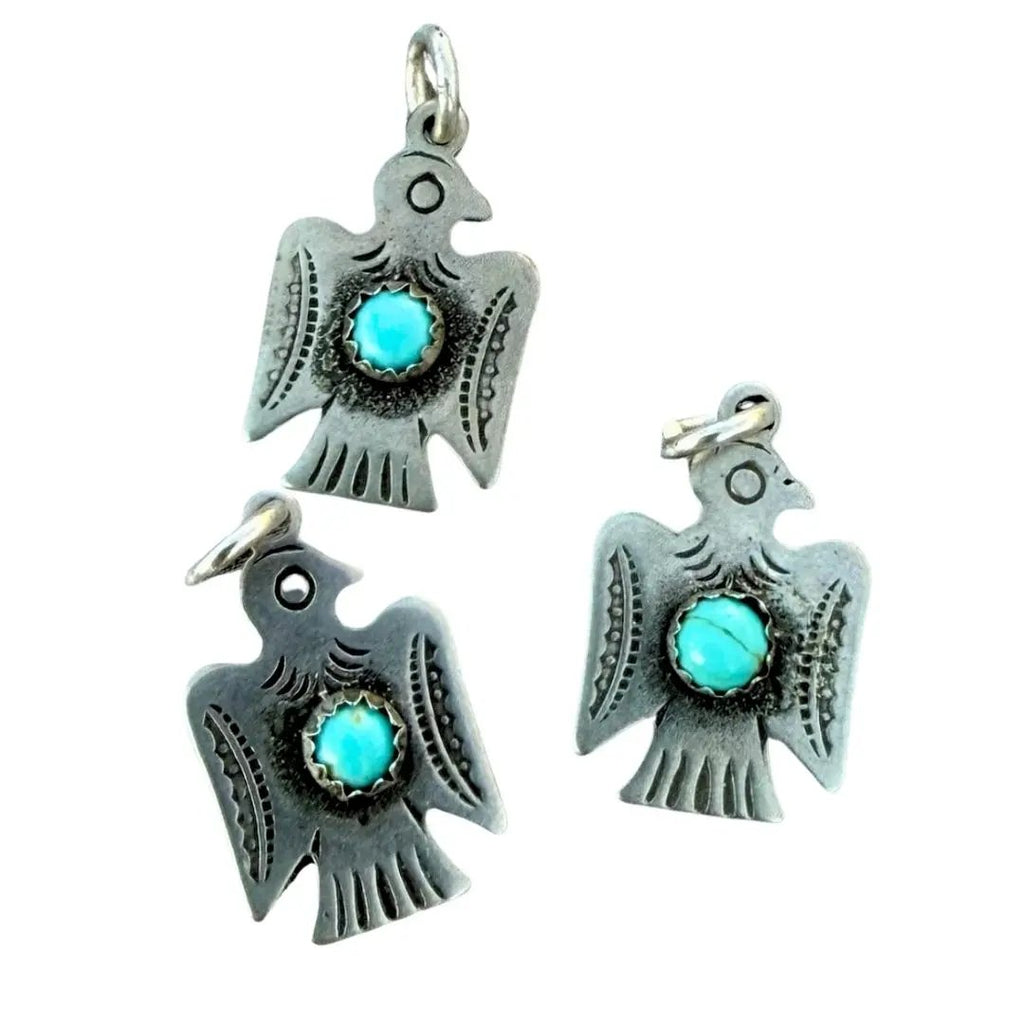 Three silver eagle pendant charms with turquoise stone centers, arranged on a plain white background.