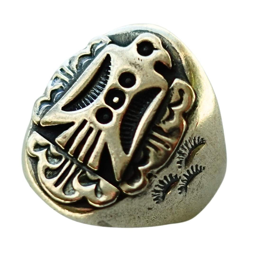 A single metallic ring with an antiqued silver finish, featuring an embossed stylized thunderbird design on a rounded, shield-like face, isolated on a white background.
