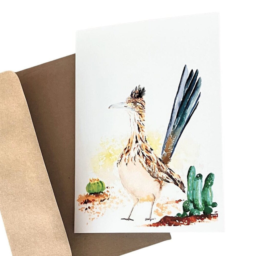 A watercolor-style greeting card featuring a roadrunner bird with cacti, shown with a brown kraft envelope on a white background.