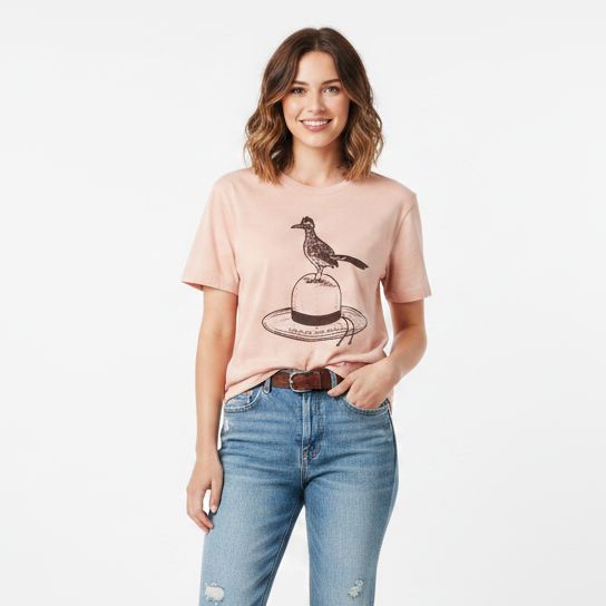 A woman modeling a light pink graphic t-shirt with a roadrunner design, paired with light-wash distressed blue jeans.