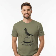 A man wearing an olive green t-shirt with a black graphic of a roadrunner bird perched on a hat