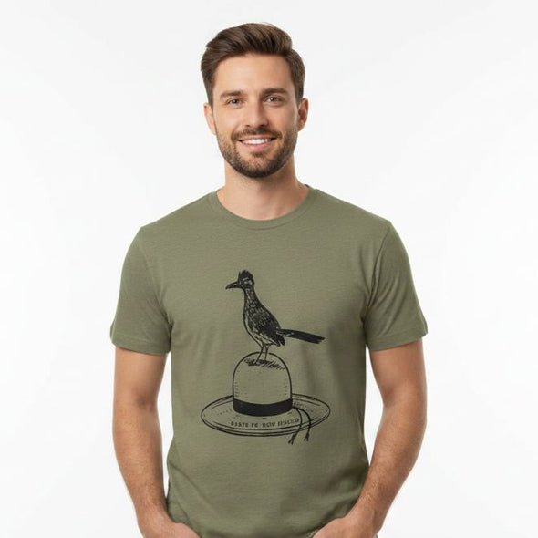 A man wearing an olive green t-shirt with a black graphic of a roadrunner bird perched on a hat
